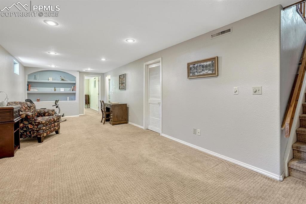 Image 24 of 38: Sitting room featuring built in shelves, carpet, and recessed lighting