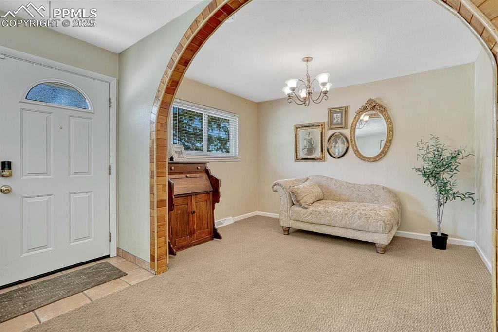 Image 3 of 38: Entryway featuring arched walkways, light carpet, a chandelier, and light t