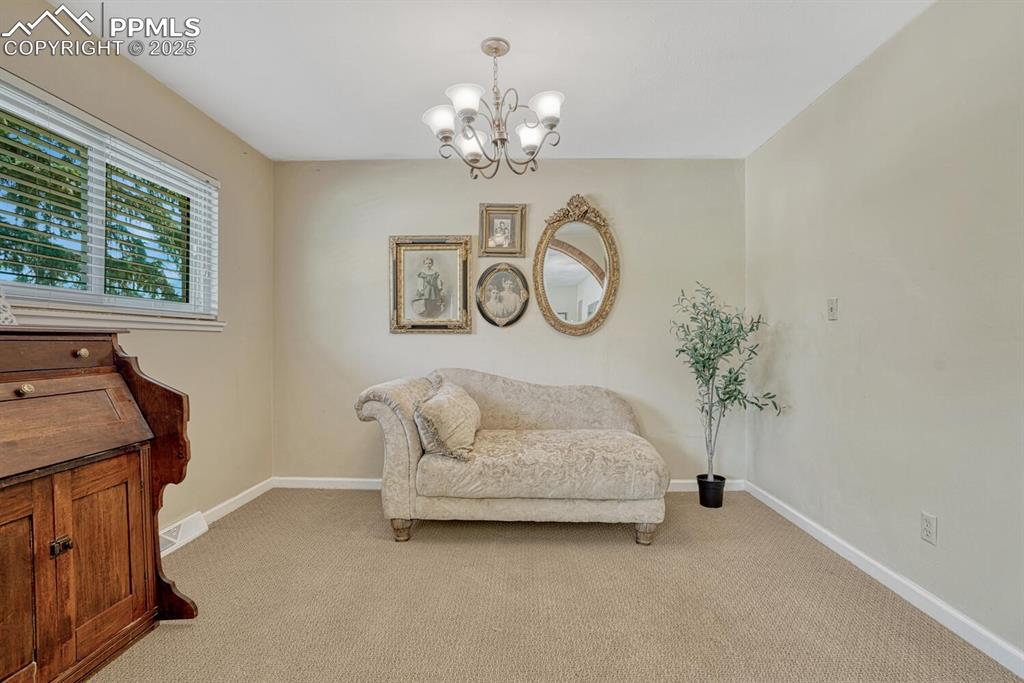 Image 4 of 38: Living area featuring light colored carpet and a chandelier
