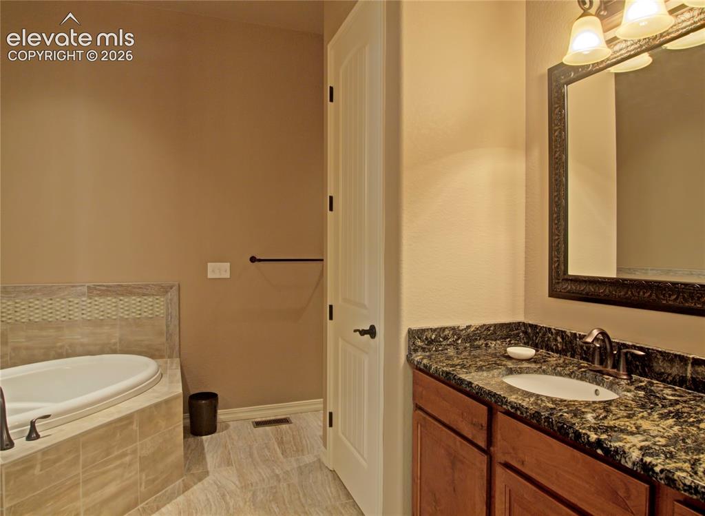 Image 21 of 33: Bathroom featuring  5 piece bath and a built-in soaking tub with tile surro