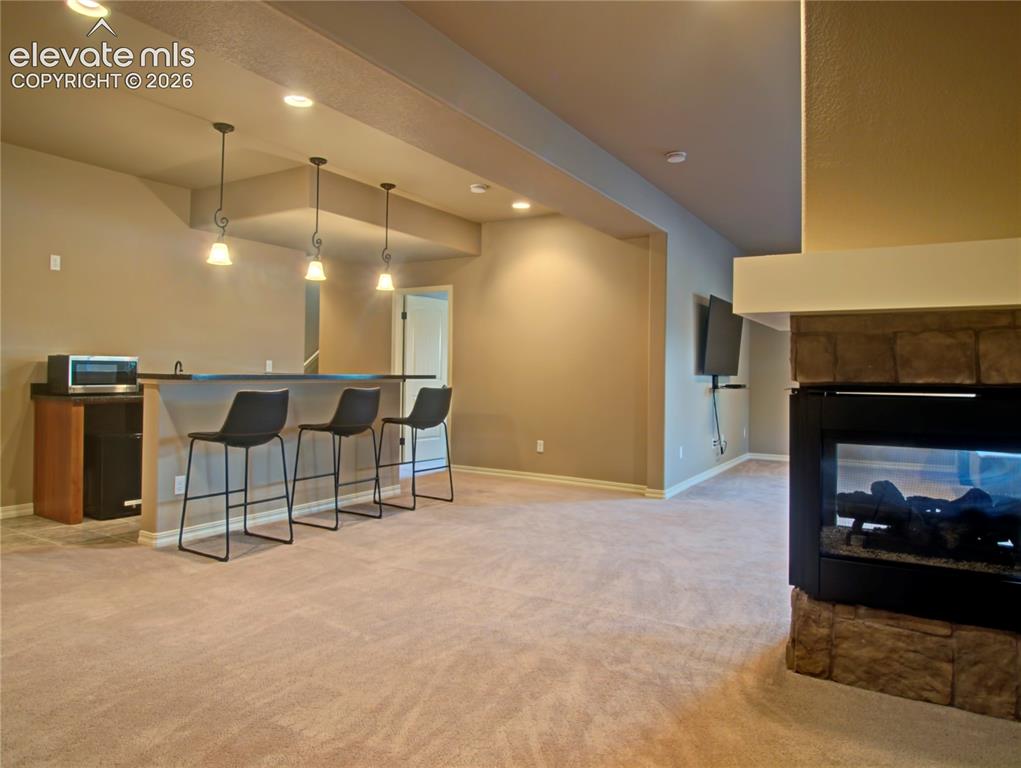 Image 33 of 33: Entertainment area with a wet bar, counter bar ,refrigerator and space for 