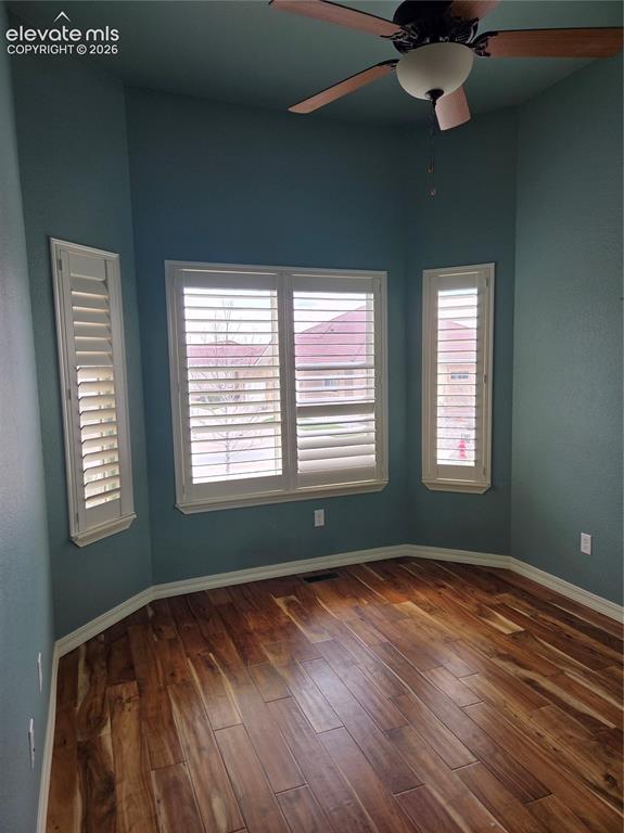 Image 6 of 33: Bay window with plantation shutters, wood-finish flooring, ceiling fan with