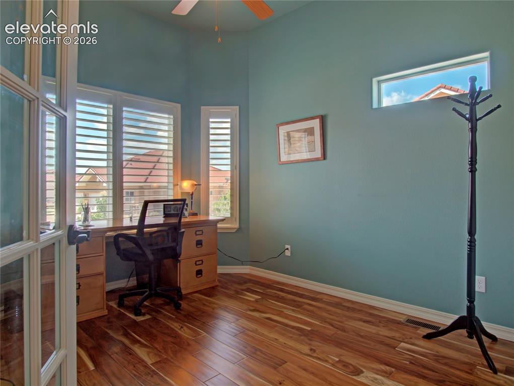 Image 7 of 33: Bedroom or office. featuring wood-finish flooring, high ceilings, and a cei