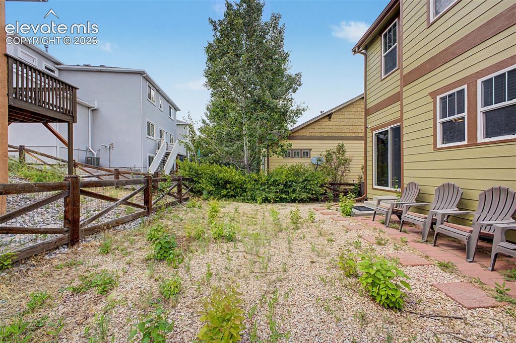 Image 35 of 35: Expansive gravel yard with a wooden split-rail fence and mature trees