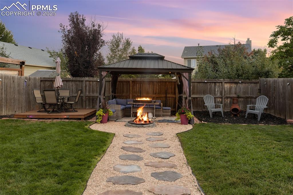 Image 11 of 39: Fenced backyard with a gazebo, a deck, an outdoor fire pit, and a patio