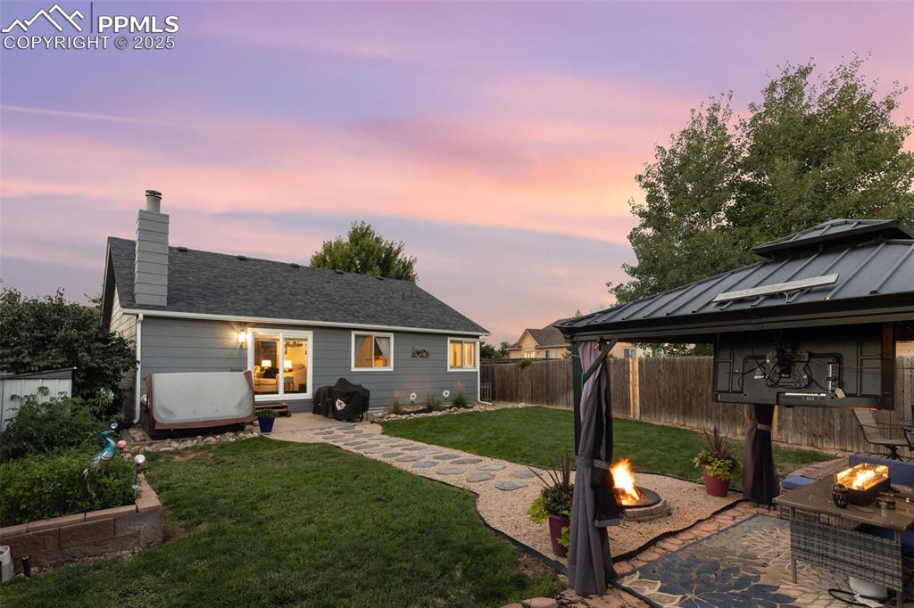 Image 12 of 39: Back of property featuring a patio, an outdoor fire pit, a gazebo, a chimne