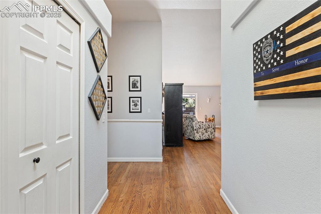 Image 18 of 39: Corridor featuring wood finished floors, a textured wall, and lofted ceilin