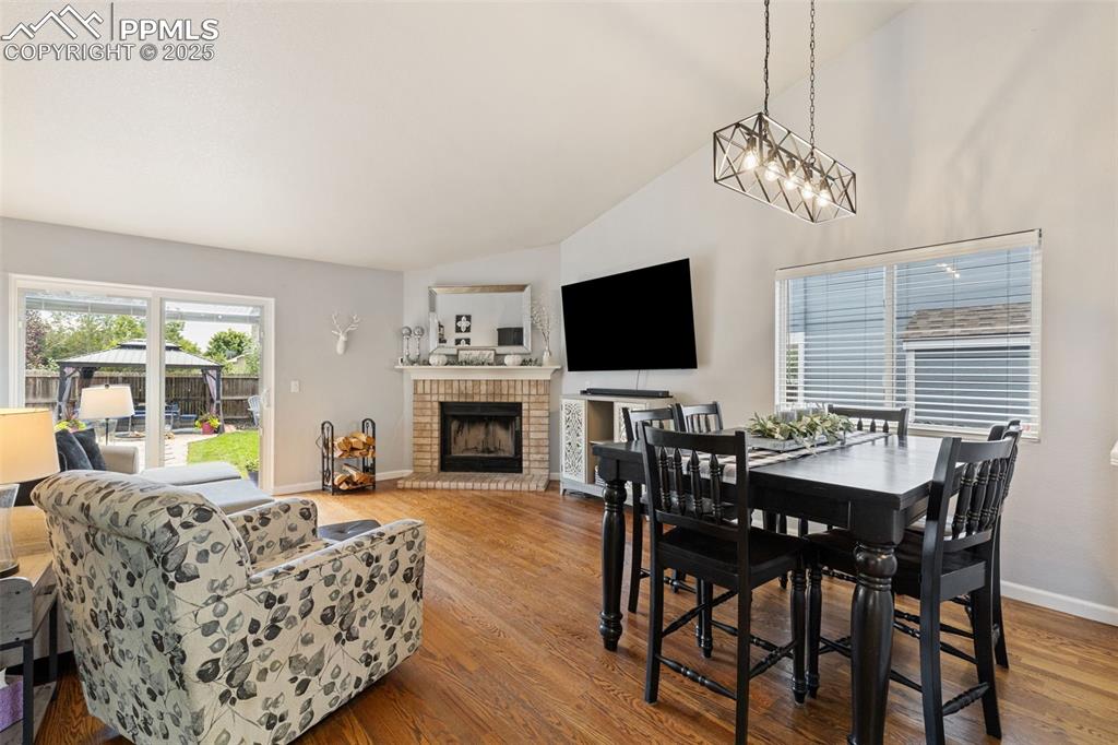 Image 19 of 39: Dining area featuring a brick fireplace, light wood-type flooring, and high
