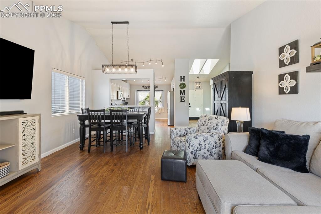 Image 20 of 39: Living area with wood finished floors and high vaulted ceiling