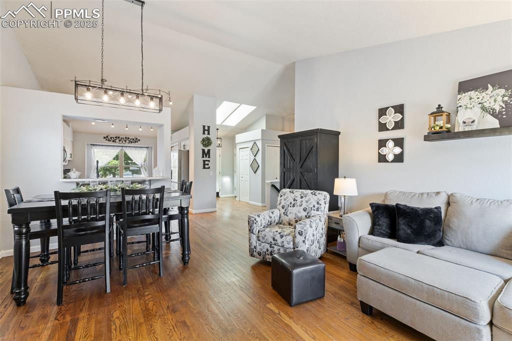 Image 21 of 39: Living room with wood finished floors and high vaulted ceiling