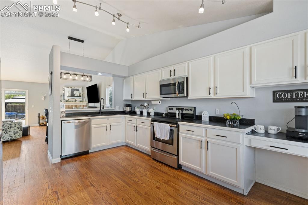 Image 23 of 39: Kitchen featuring dark countertops, white cabinetry, stainless steel applia