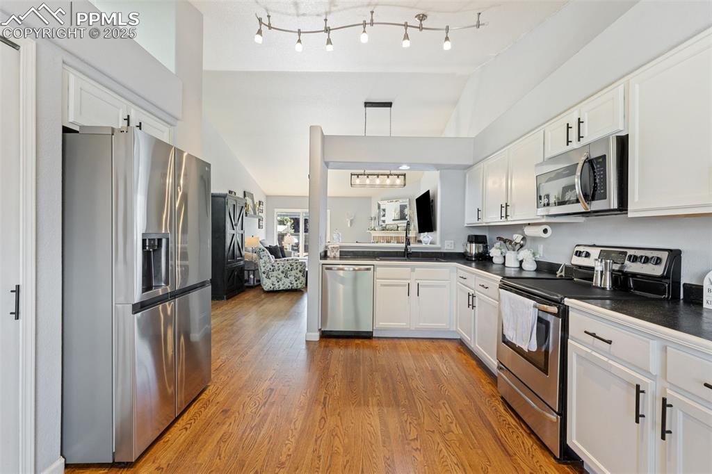 Image 24 of 39: Kitchen featuring stainless steel appliances, white cabinets, open floor pl