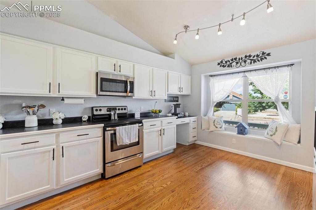 Image 25 of 39: Kitchen featuring dark countertops, appliances with stainless steel finishe
