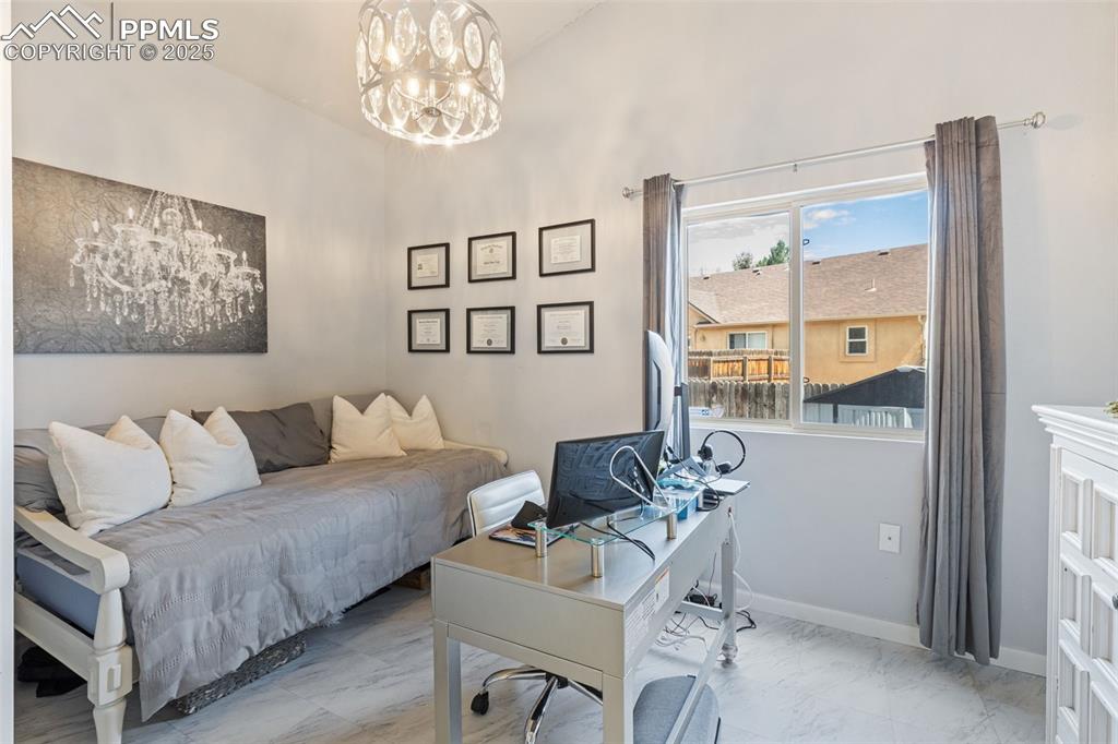Image 26 of 39: Office space with marble finish flooring and a chandelier