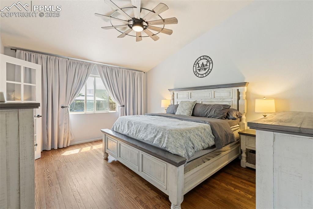Image 27 of 39: Bedroom with vaulted ceiling, hardwood / wood-style floors, and a ceiling f