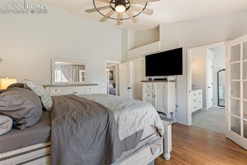 Image 28 of 39: Bedroom with light wood-type flooring, high vaulted ceiling, ceiling fan, e