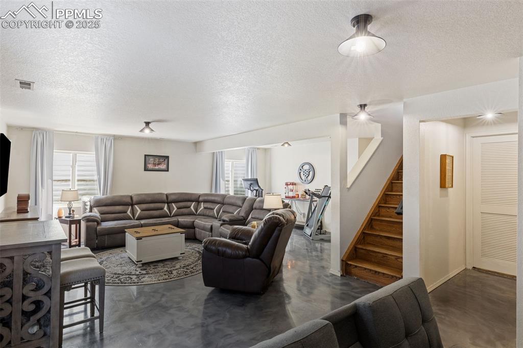 Image 33 of 39: Living room featuring a textured ceiling, finished concrete flooring, and s