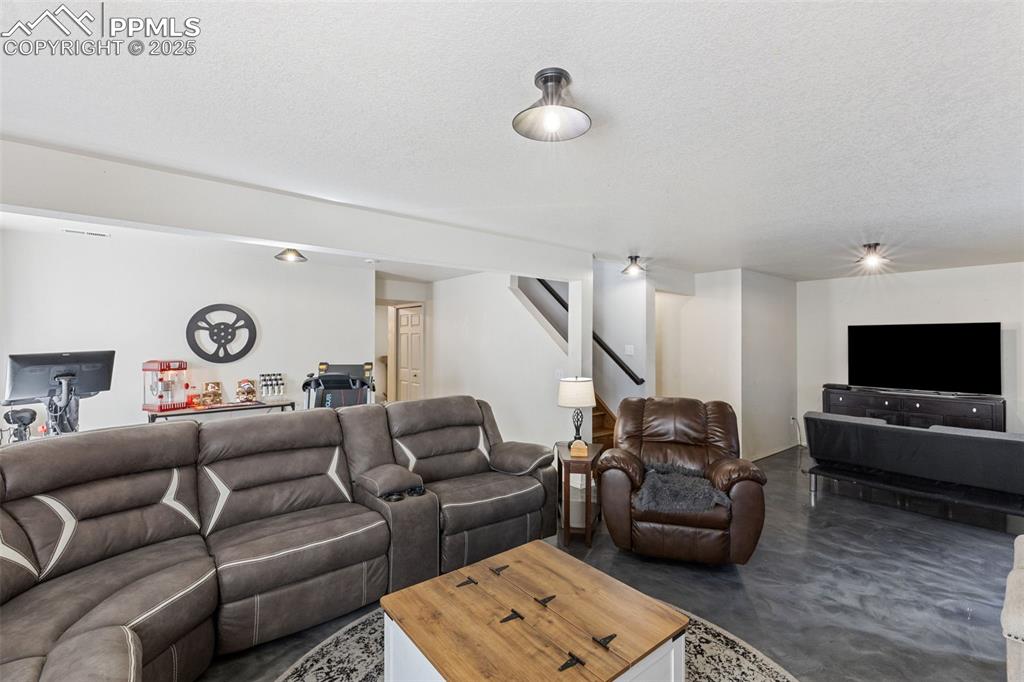 Image 34 of 39: Living area featuring concrete floors, a textured ceiling, and stairway