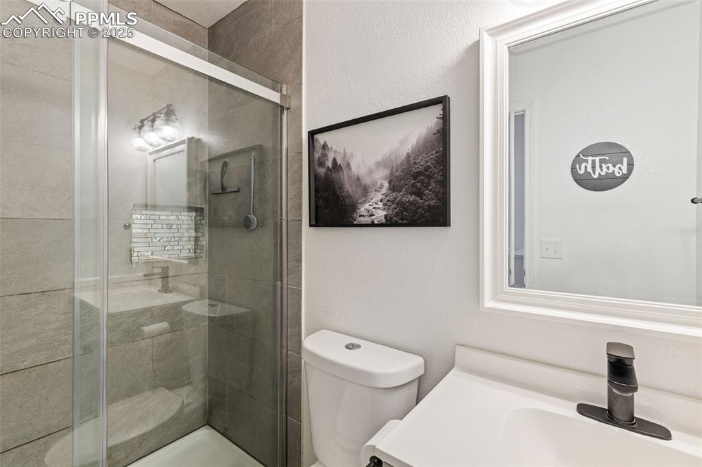 Image 36 of 39: Full bath with a textured wall, a stall shower, and vanity