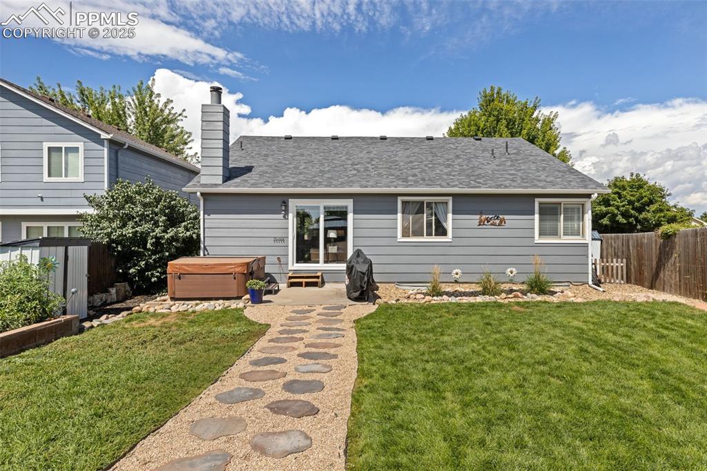 Image 38 of 39: Back of property featuring a fenced backyard, a patio area, a hot tub, roof