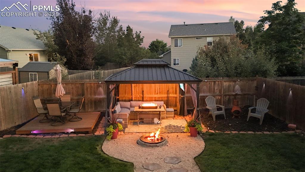 Image 7 of 39: Yard at dusk with a gazebo, a patio, an outdoor living space with a fire pi