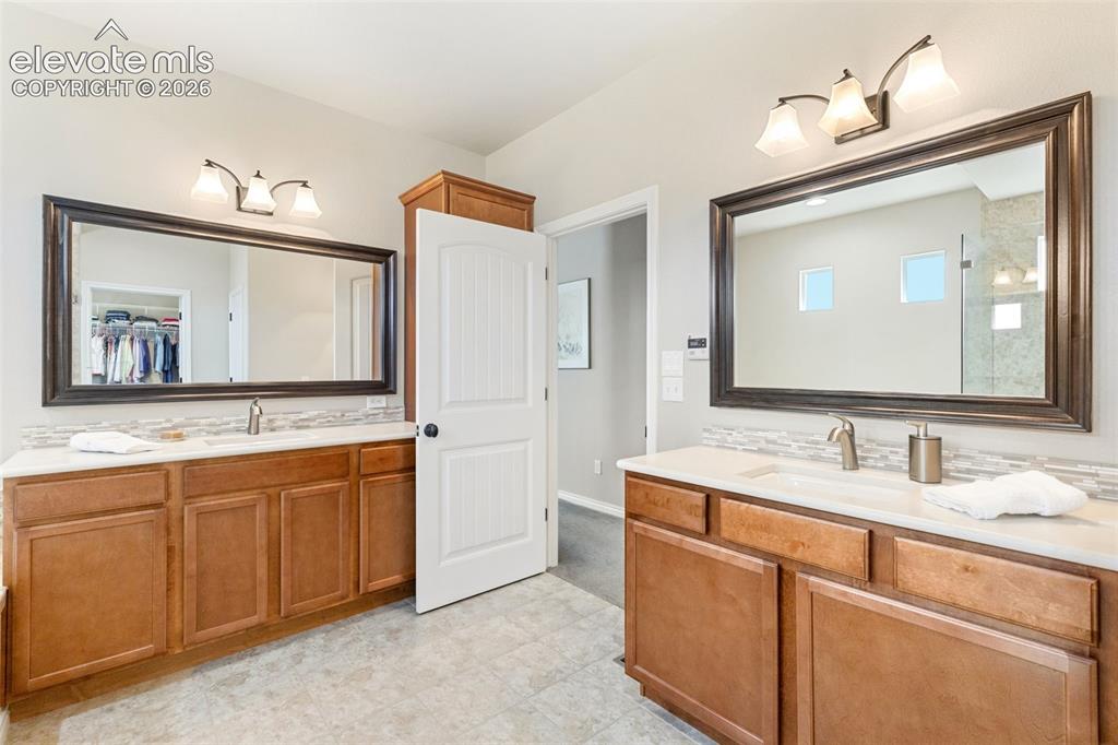 Image 23 of 49: Dual vanities in primary bath featuring quartz countertops