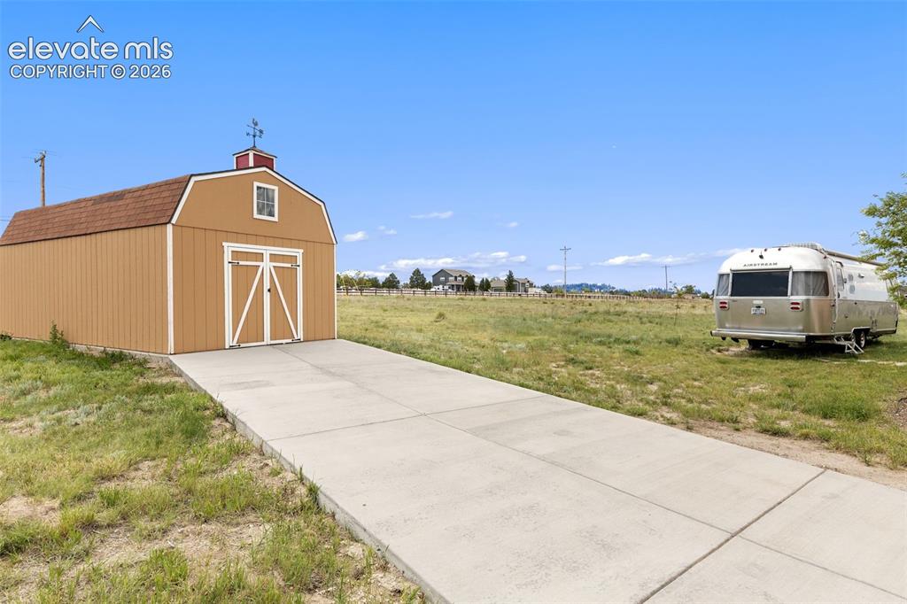 Image 44 of 49: Shed on concrete pad at end of driveway provides extra storage