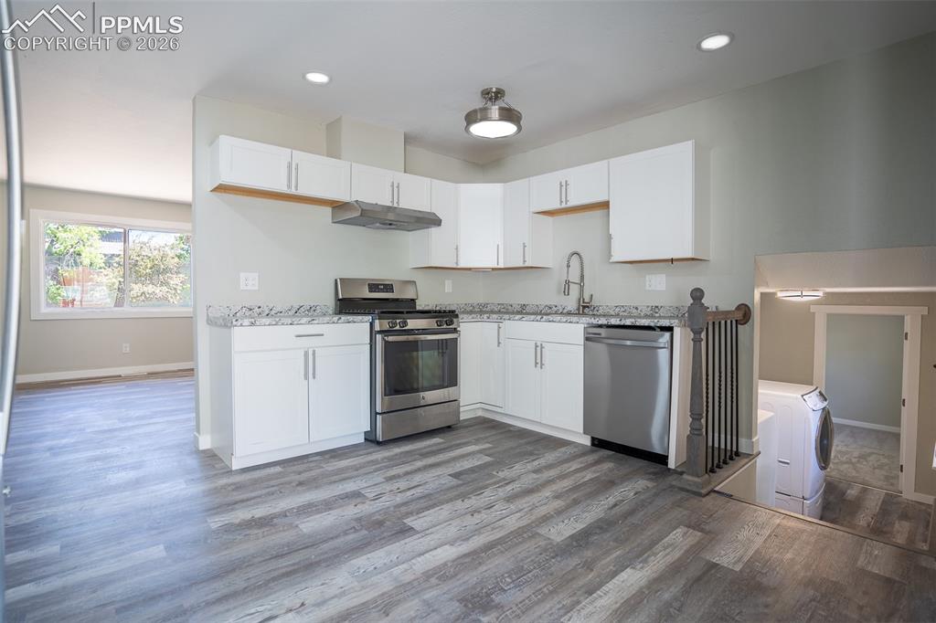 Image 8 of 24: Open concept kitchen showing entry to living room and basement laundry