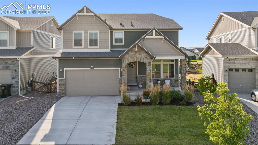 Caption: Craftsman inspired home featuring stone siding, driveway, roof with shingles, and an attached garage