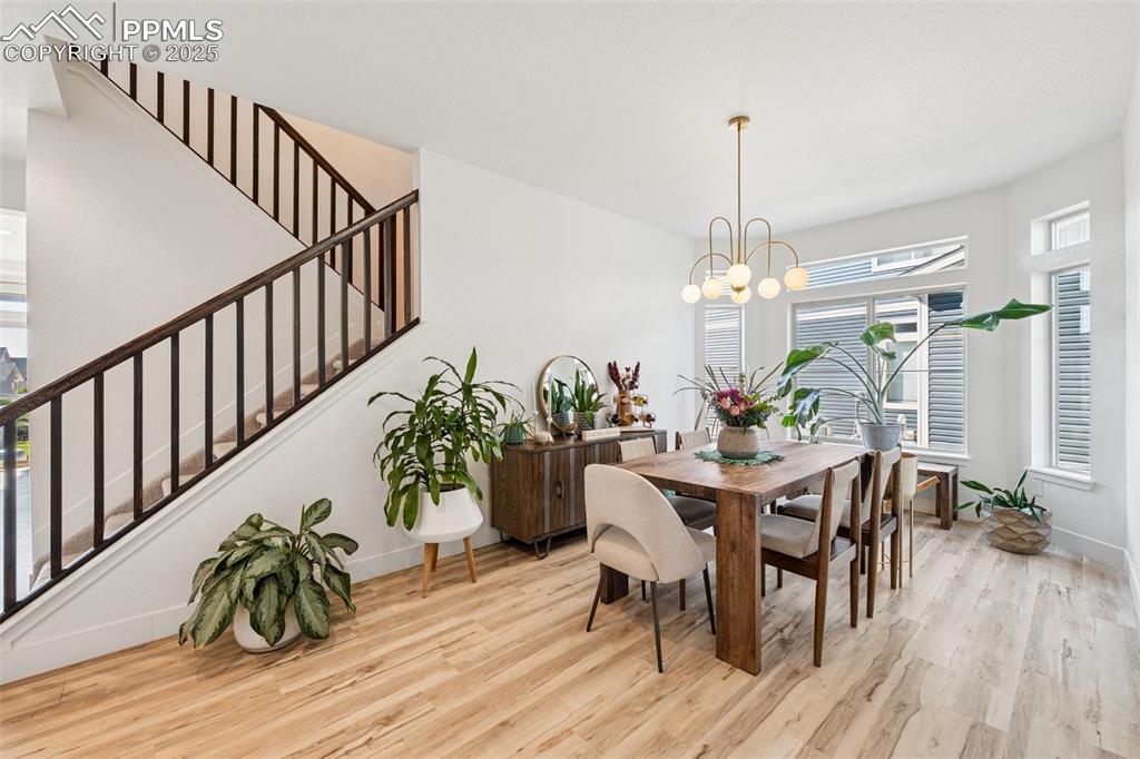 Image 10 of 43: Dining space with light wood finished floors and stairway