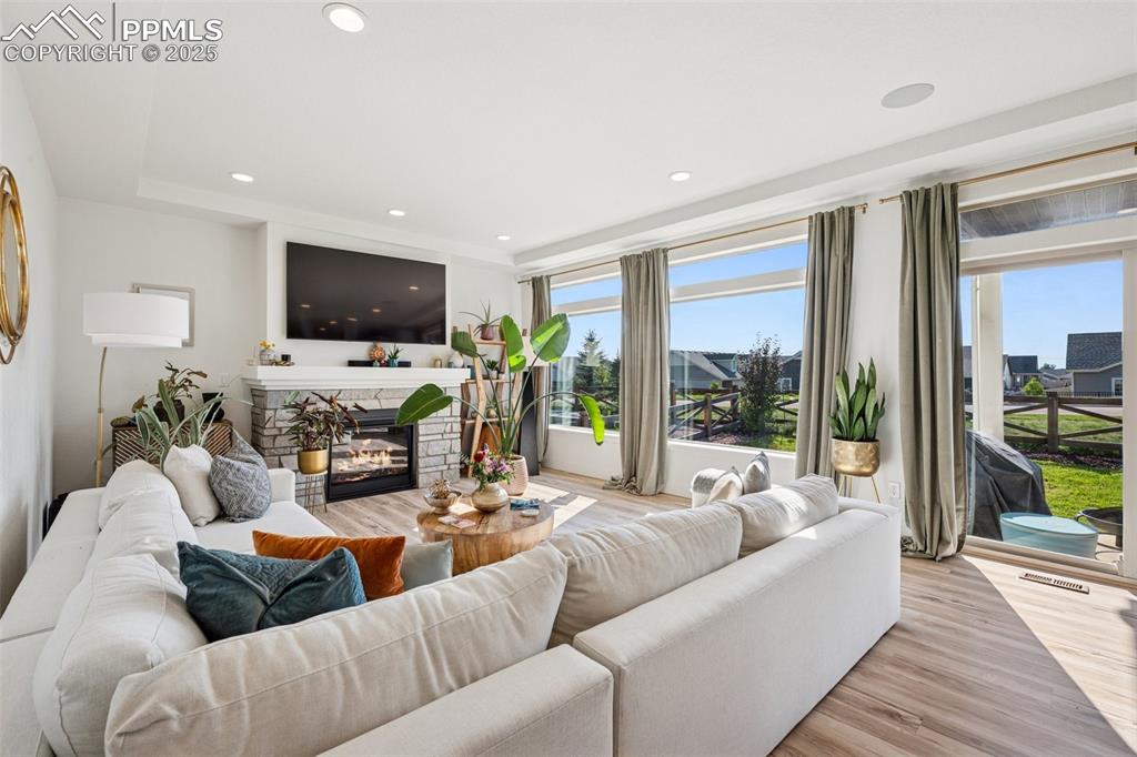 Image 17 of 43: Living room with a fireplace, light wood finished floors, and recessed ligh