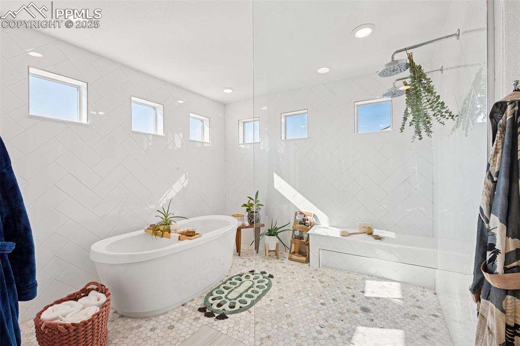 Image 22 of 43: Bathroom with tile walls, a soaking tub, plenty of natural light, a walk in