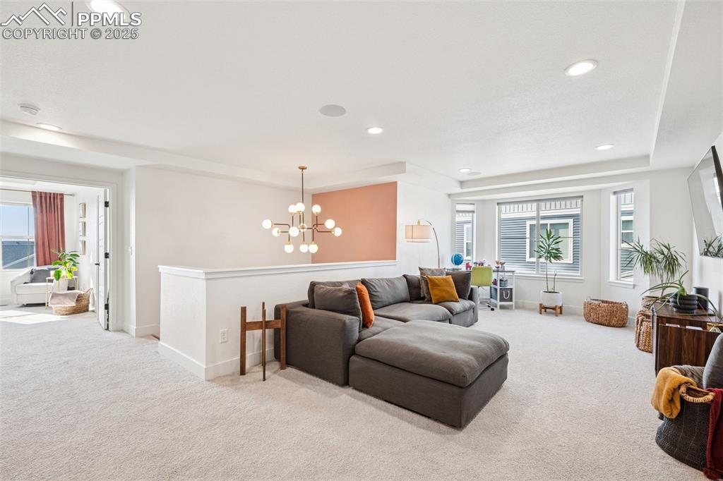 Image 23 of 43: Carpeted living area with recessed lighting, a chandelier, and a tray ceili
