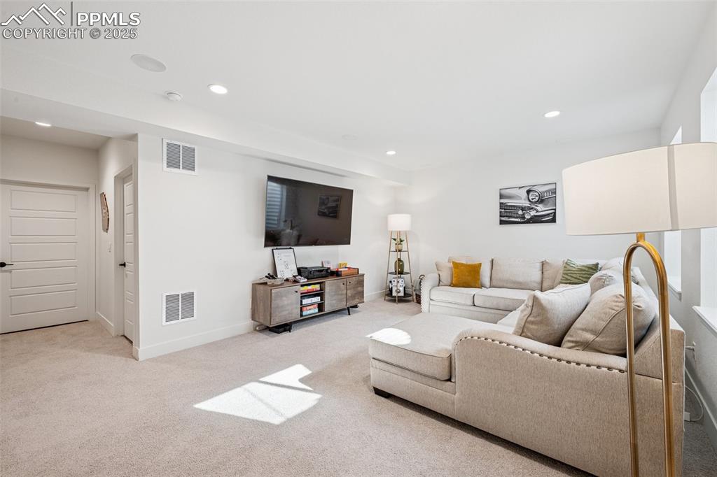 Image 36 of 43: Living area with recessed lighting and light colored carpet