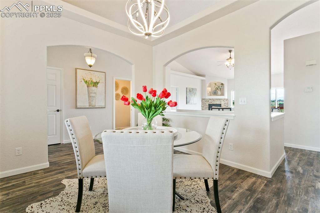 Image 11 of 44: Dining room with arched walkways, a chandelier, wood finished floors, a cei