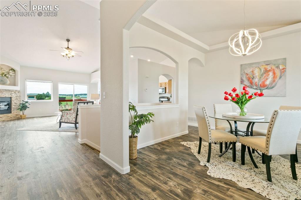 Image 13 of 44: Dining room with wood finished floors, a chandelier, a ceiling fan, arched