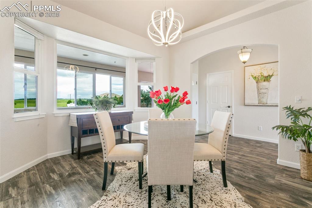 Image 15 of 44: Dining room featuring arched walkways, a chandelier, and wood finished floo