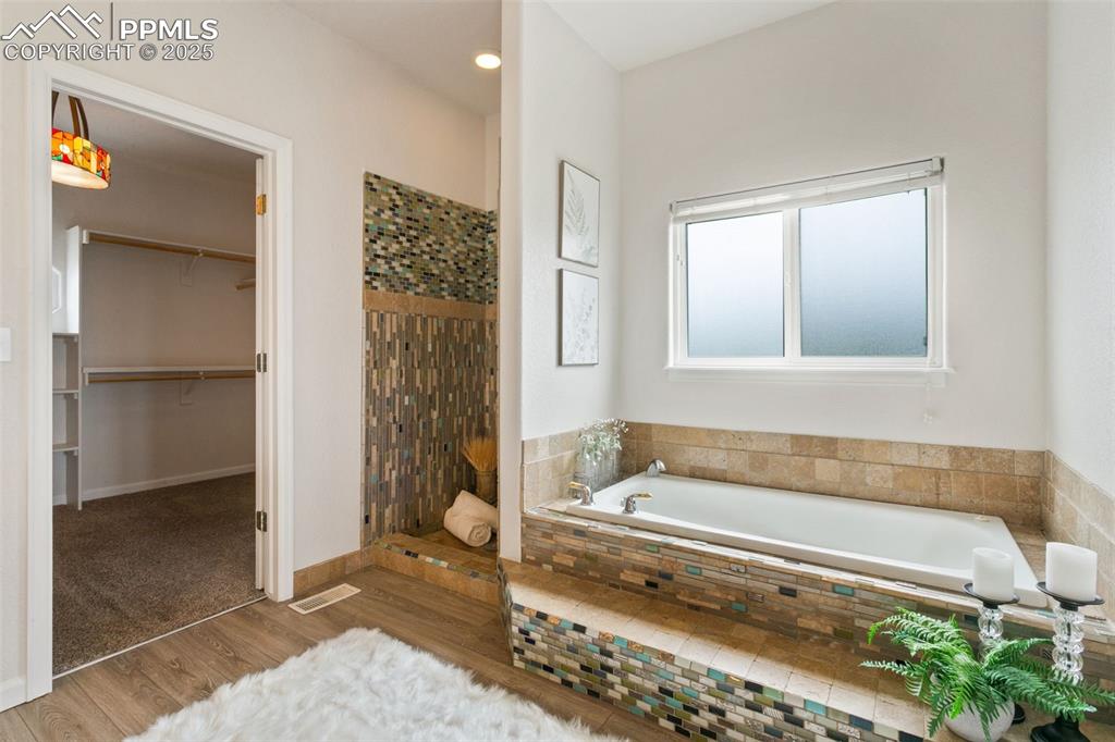 Image 22 of 44: Bathroom with a shower stall, wood finished floors, a bath, a spacious clos