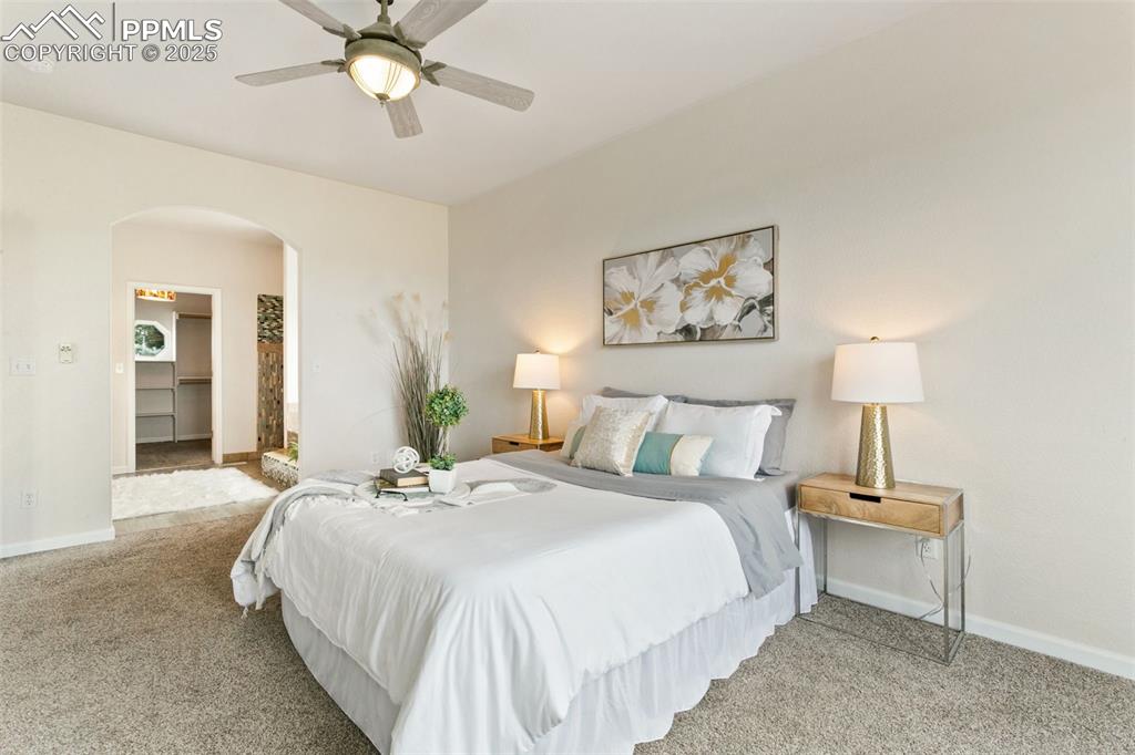 Image 24 of 44: Carpeted bedroom with arched walkways, a spacious closet, and ceiling fan