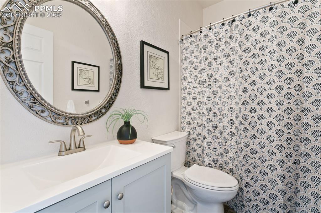 Image 27 of 44: Full bathroom with vanity, a textured wall, and curtained shower