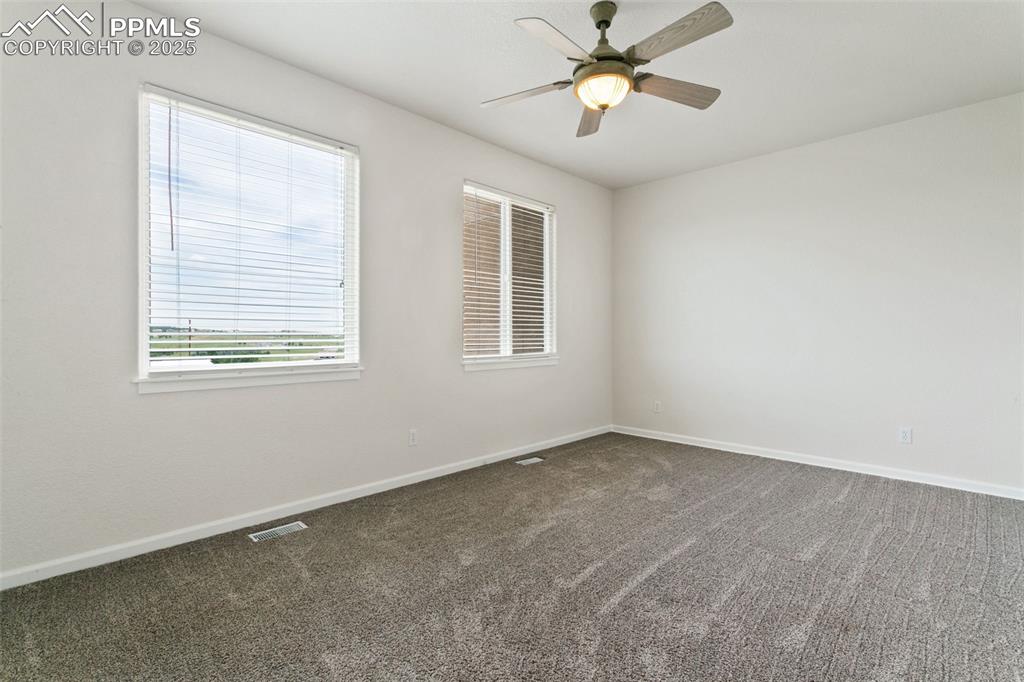 Image 28 of 44: Spare room featuring dark carpet and ceiling fan
