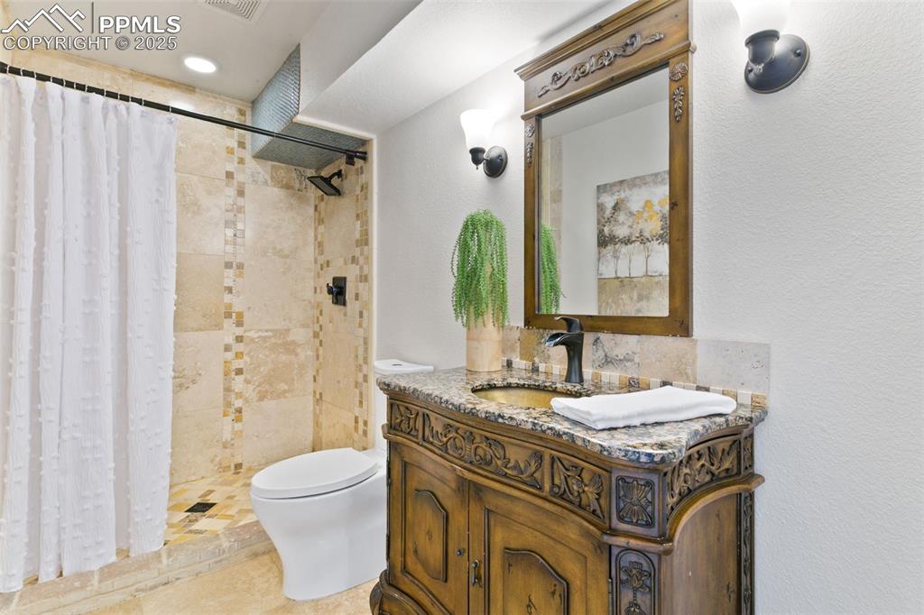 Image 31 of 44: Bathroom with a textured wall, vanity, and a tile shower