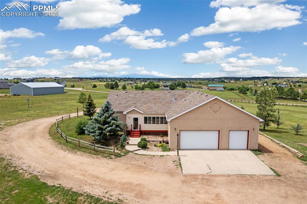 Image 44 of 44: View of front of house with driveway, a rural view, stucco siding, and a ga