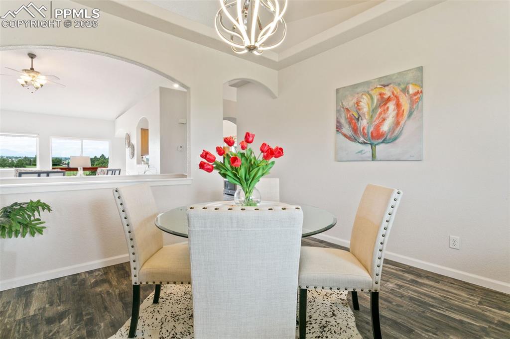 Image 8 of 44: Dining room with wood finished floors, a ceiling fan, a chandelier, and arc