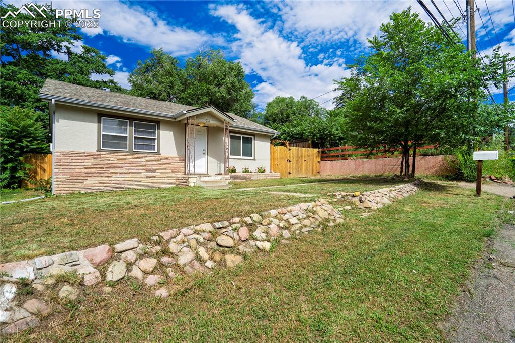 Caption: View of front facade with stone siding, stucco siding, and roof with shingles