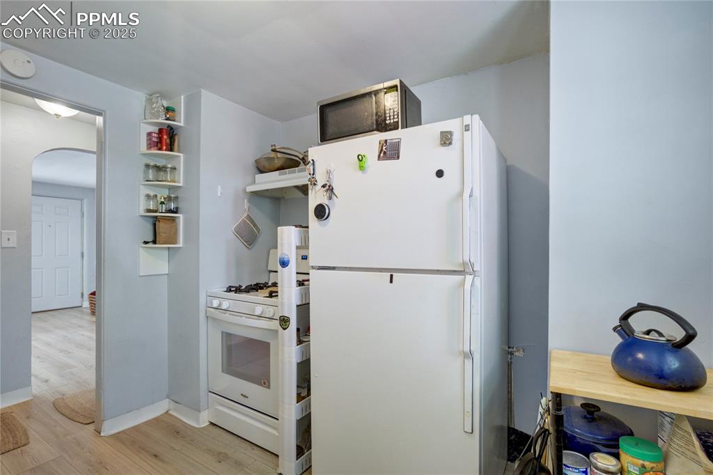 Image 12 of 28: Kitchen featuring white appliances, wood finished floors, arched walkways, 
