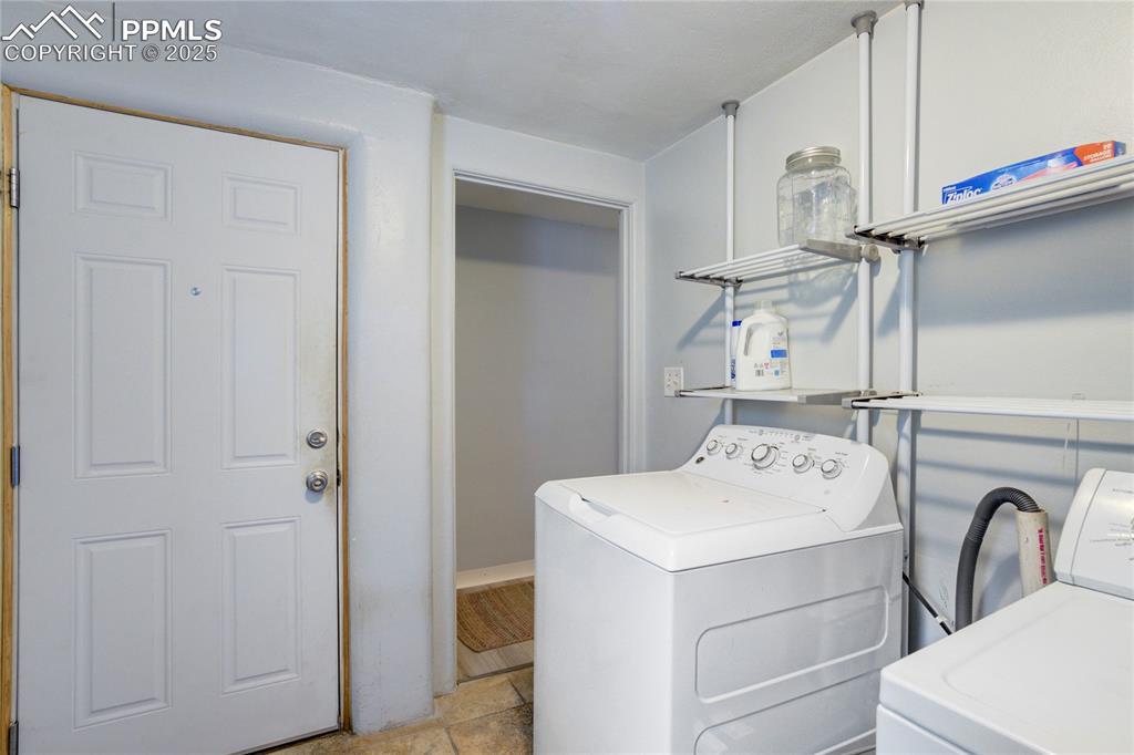 Image 21 of 28: Laundry area featuring separate washer and dryer and light stone finish flo