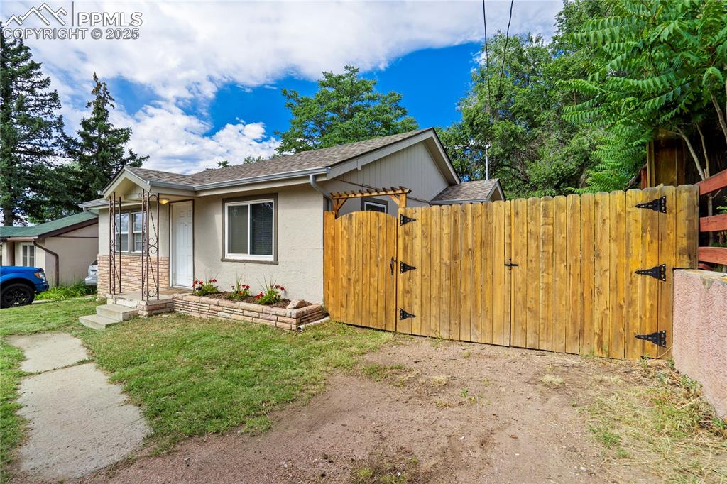 Image 3 of 28: View of front of house featuring a gate, roof with shingles, and stucco sid
