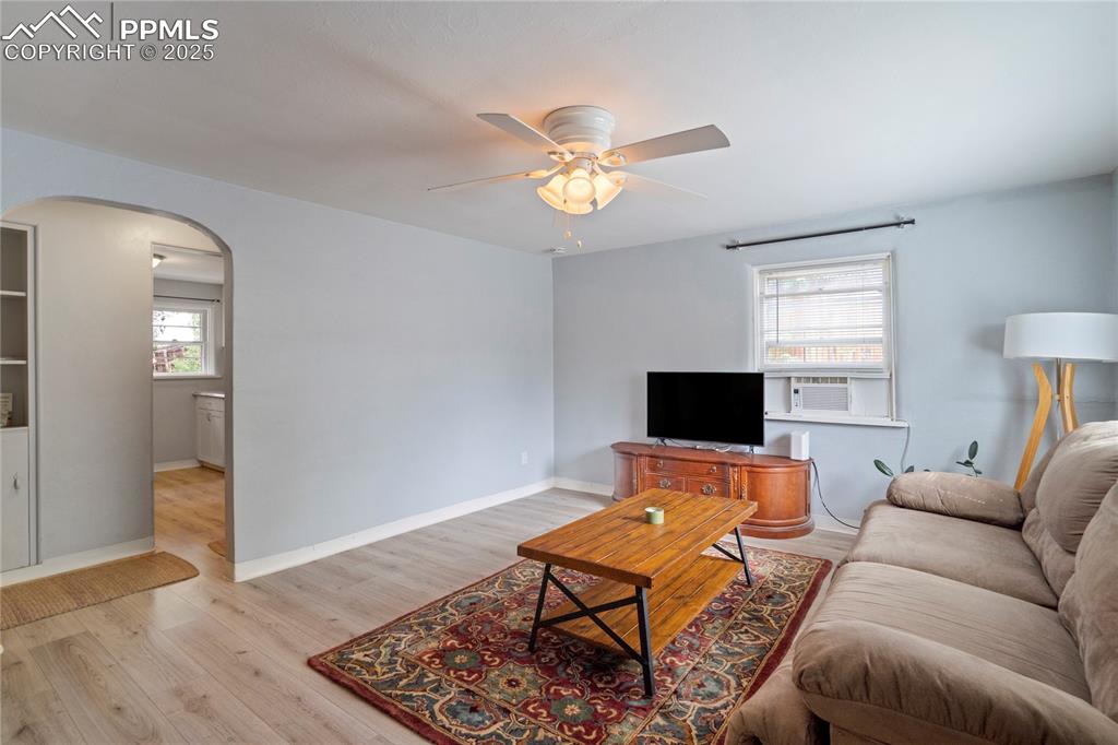 Image 7 of 28: Living area with arched walkways, a ceiling fan, and light wood finished fl