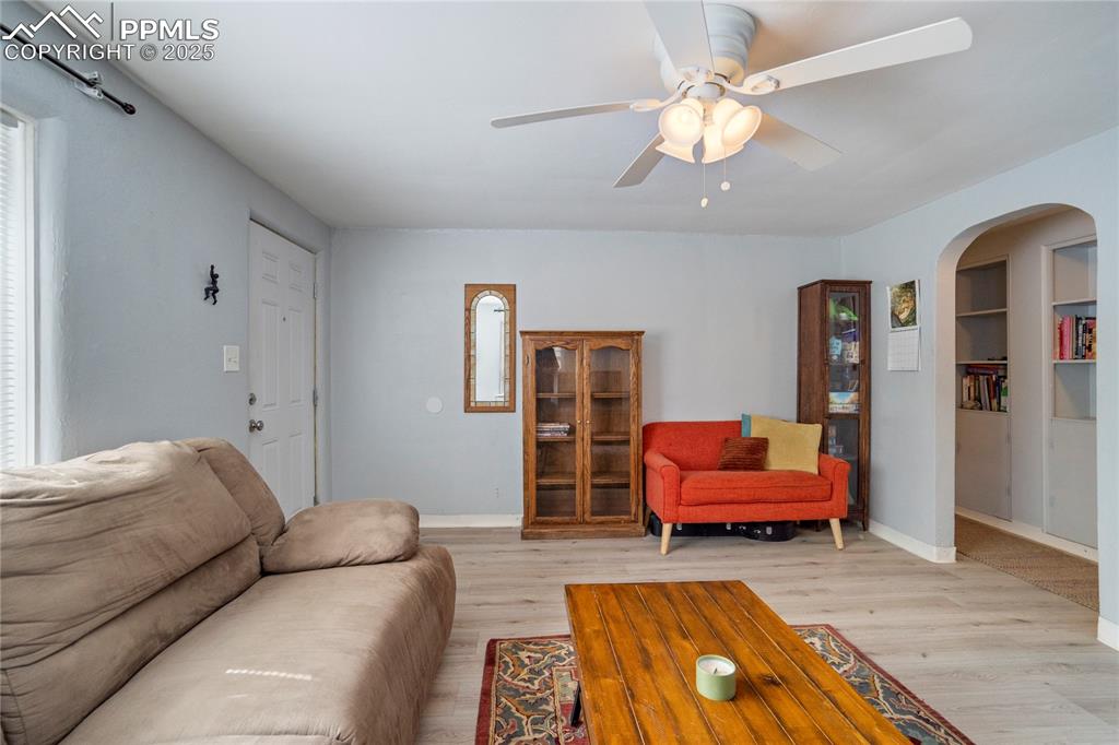 Image 8 of 28: Living area featuring arched walkways, light wood-style flooring, and ceili